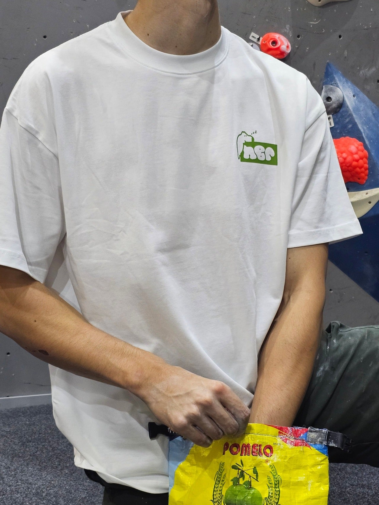 Man wearing white nobori shirt facing the camera while holding a chalk bag